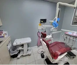 Clean and modern dental treatment room with a patient chair, overhead light, and dental equipment.